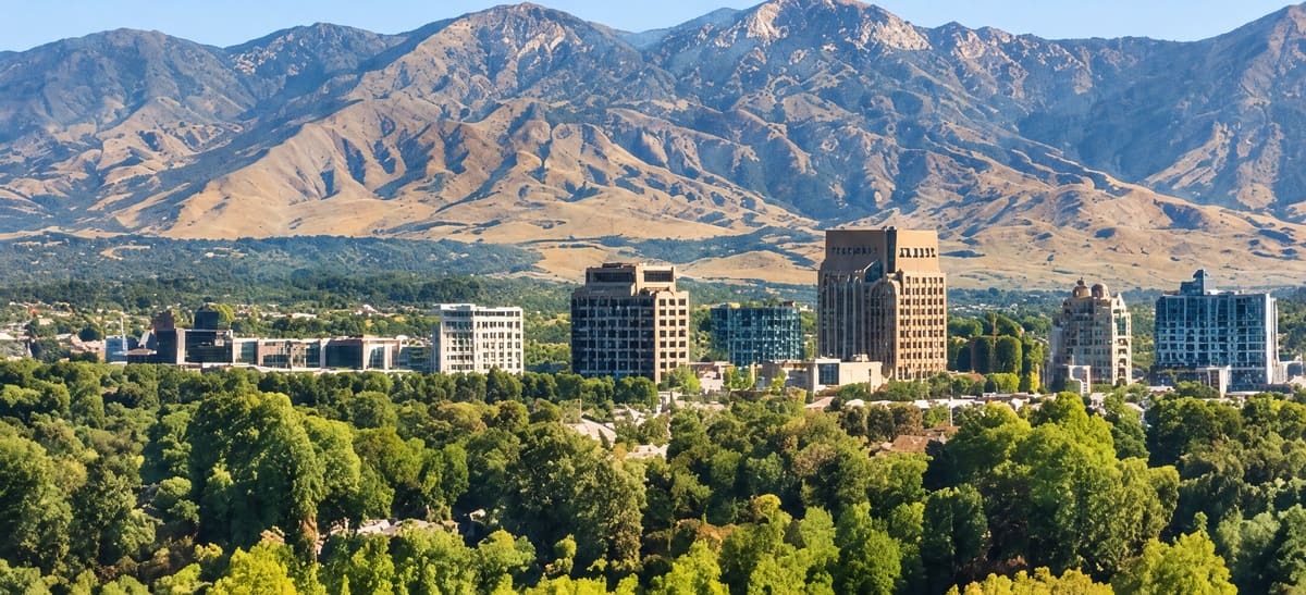 Downtown Boise skyline among green trees with the foothills behind